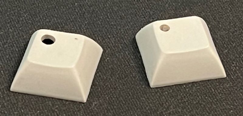 Keycaps with drilled windows, one with translucent silicon window